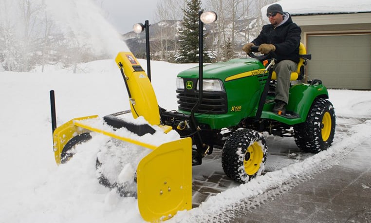 Man riding lawn mower to plow snow
