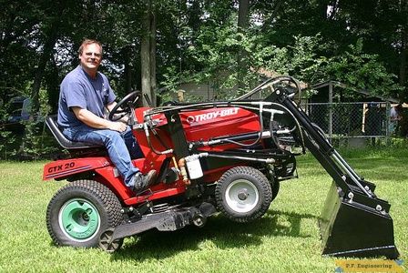 Man riding lawn mower with scoop addition