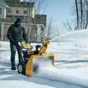 Man using his mower and snow blower to ditch snow away
