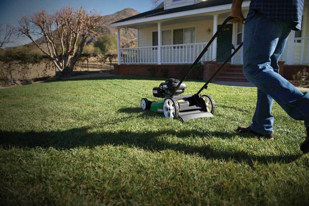 Man landscapping yard by his high wheel lawn mower